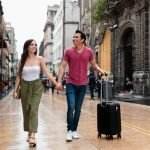 a man and a woman walking down a sidewalk with luggage