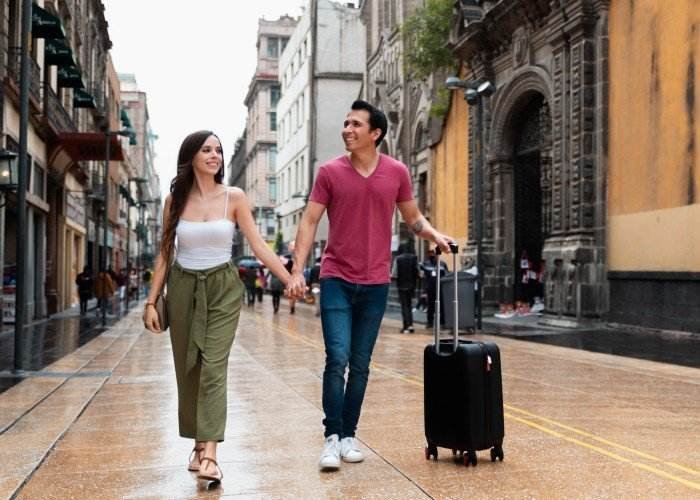a man and a woman walking down a sidewalk with luggage
