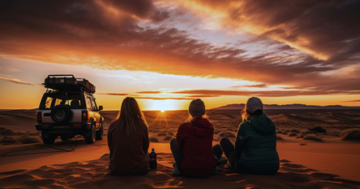 Three people sitting in the Thar Desert at sunset, enjoying a luxury desert tour adventure in Rajasthan