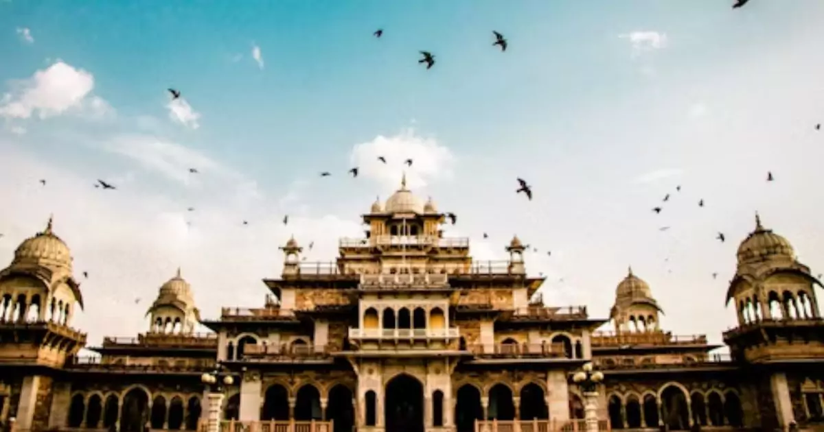 Front view of Albert Hall Museum in Jaipur with birds flying in the sky and a beautiful blue background