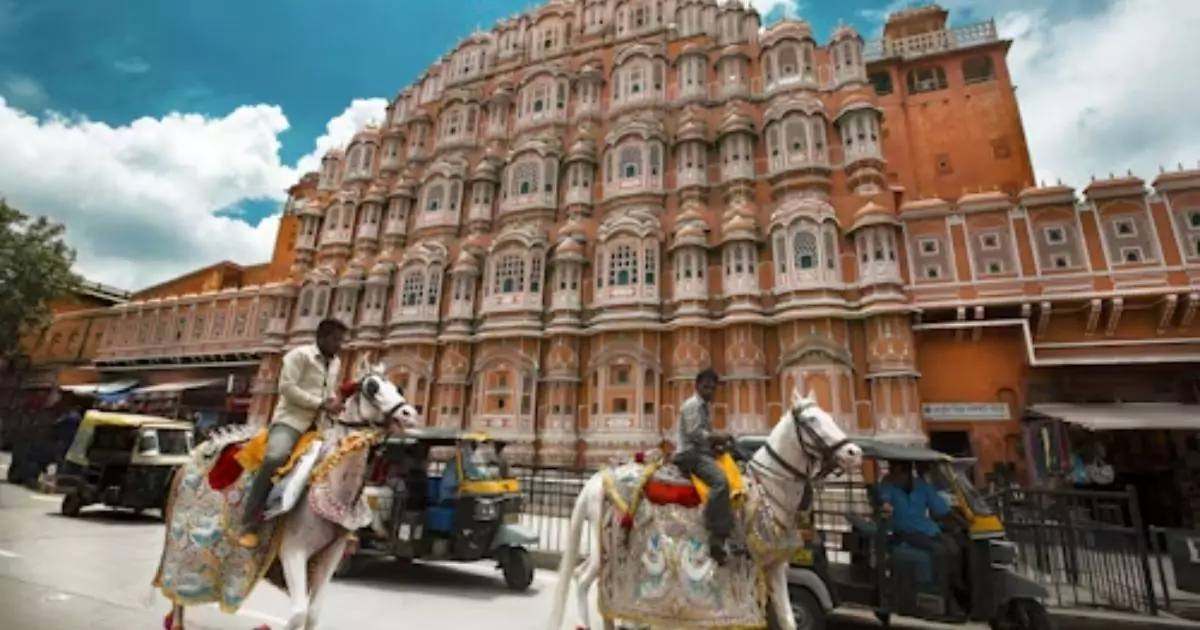 Hawa Mahal with vibrant sky and traditional horse riders in foreground 