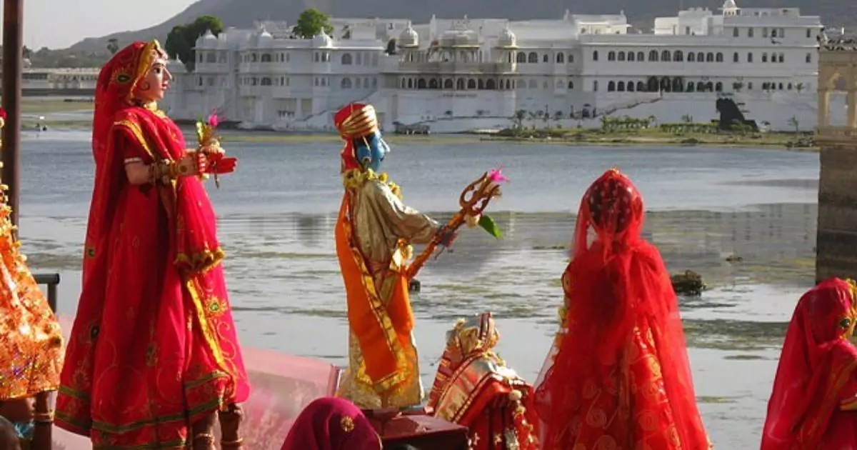 A vibrant festival scene by Udaipur's lake with colorful statues of deities and women in red attire
